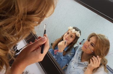 Madre y niña retocándose en tocador de maquillaje