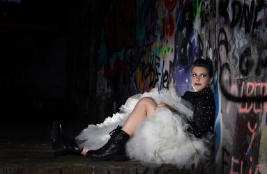 Novia sentada sobre pared de grafittis con botas moteras