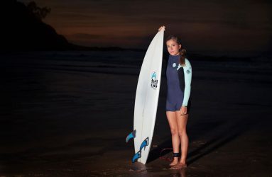 Chica con tabla de surf en la playa de noche